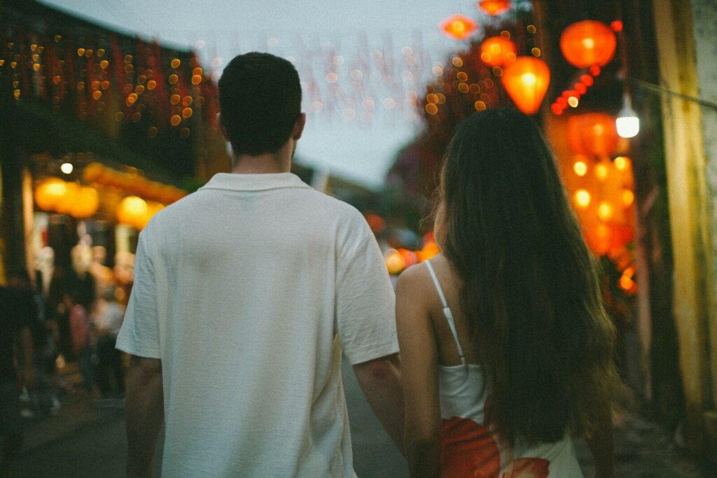 A couple walking down a street illuminated by lanterns.