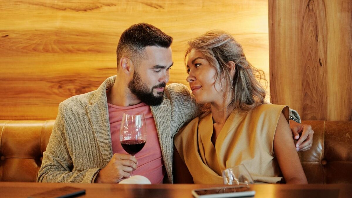 A loving couple sharing a romantic moment with red wine in a stylish restaurant.