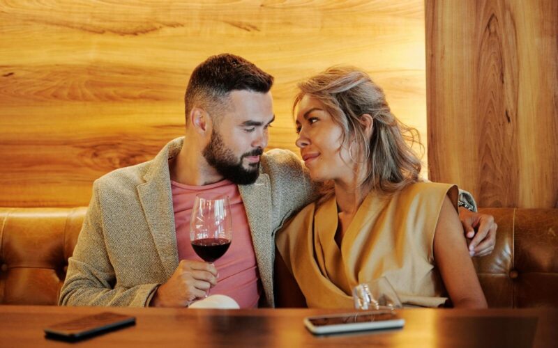 A loving couple sharing a romantic moment with red wine in a stylish restaurant.