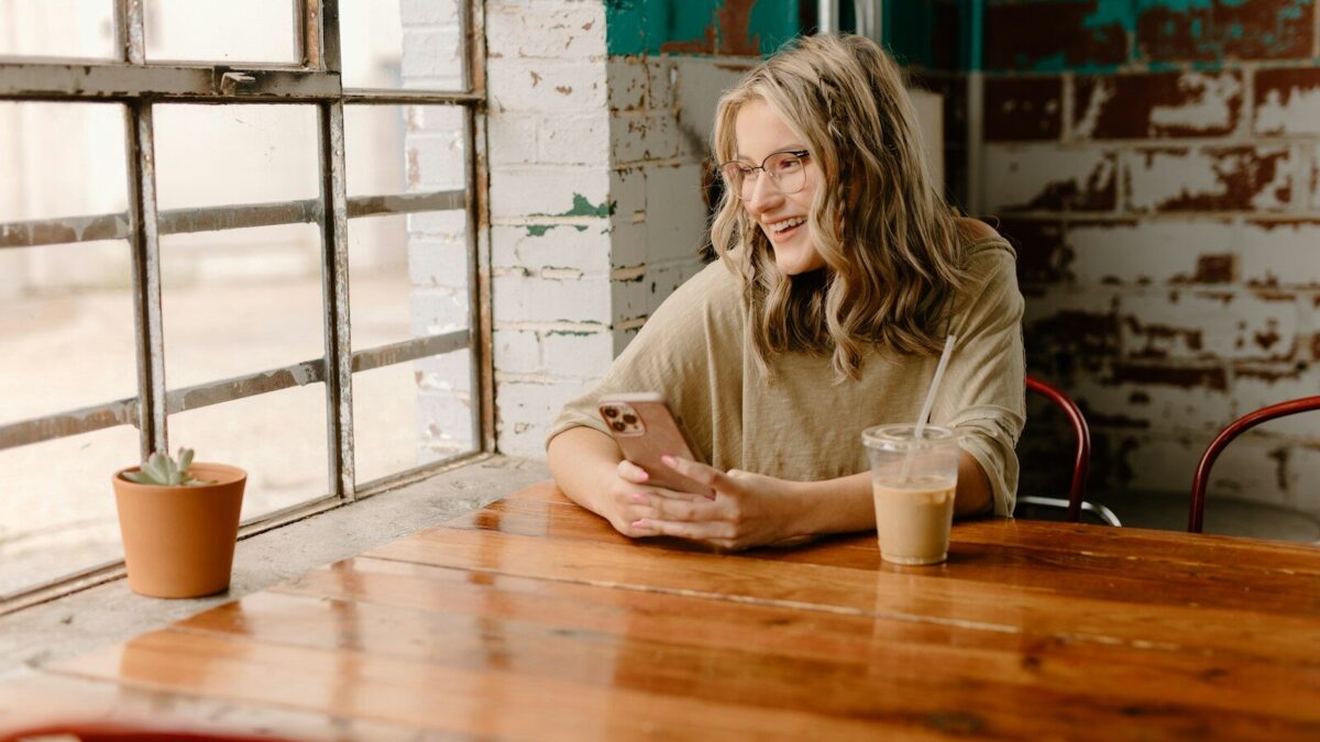 a woman sitting at a table looking at her cell phone