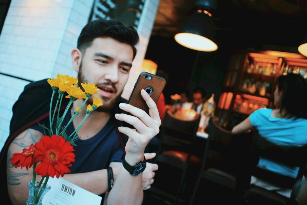 man in black tank top holding gold iphone 6