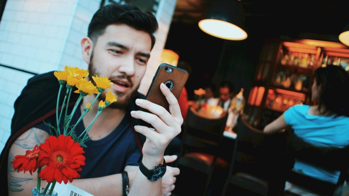 man in black tank top holding gold iphone 6