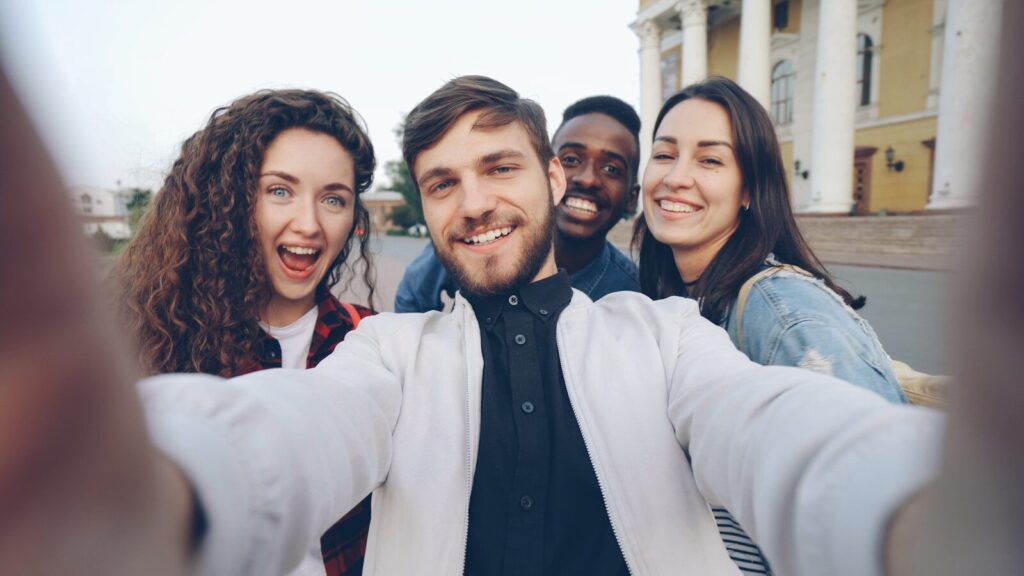 Four friends smile while taking a selfie.