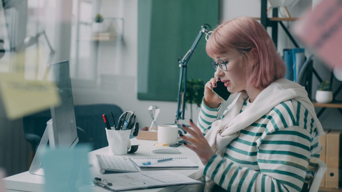 A woman sitting at a desk talking on a cell phone