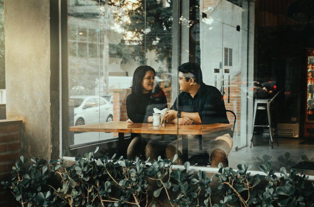 a man and a woman sitting at a table in front of a window