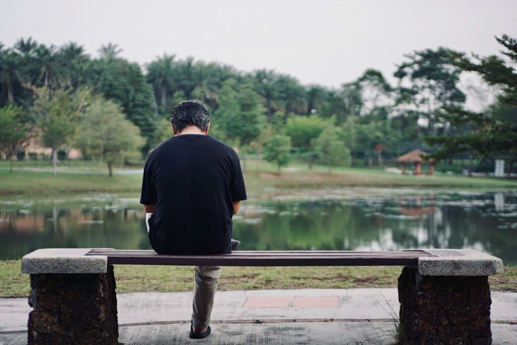 man in black shirt standing on brown wooden dock near lake during daytime