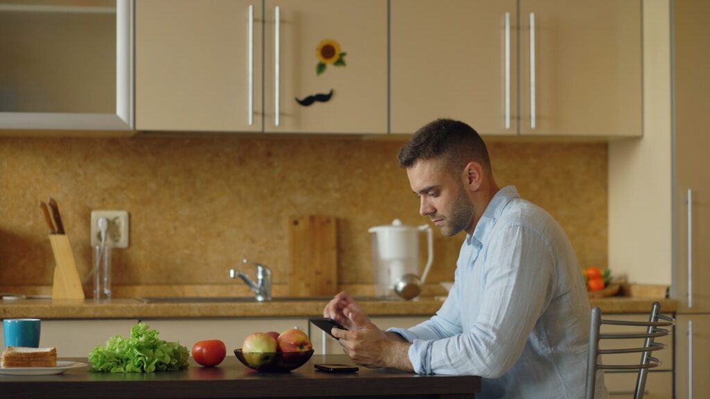 Man sitting at kitchen table with phone