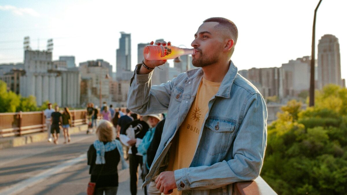 man in blue denim jacket holding brown ceramic mug