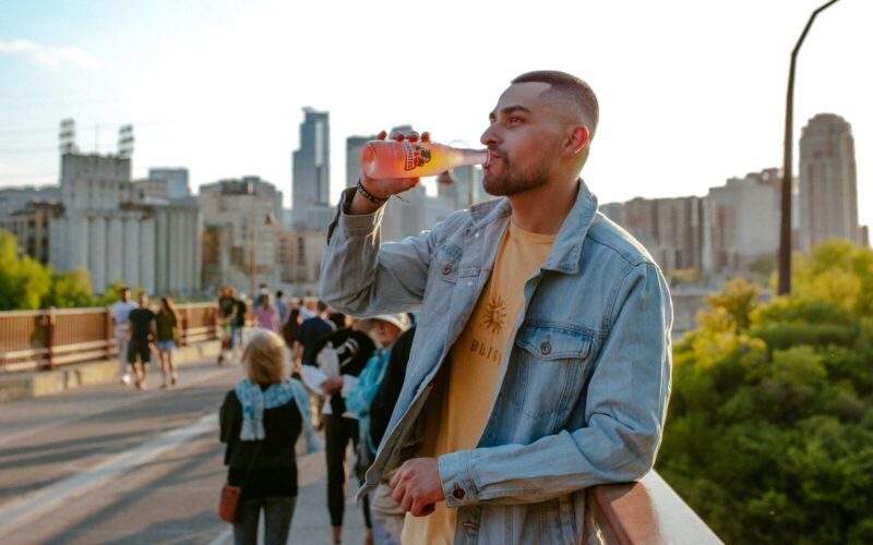 man in blue denim jacket holding brown ceramic mug