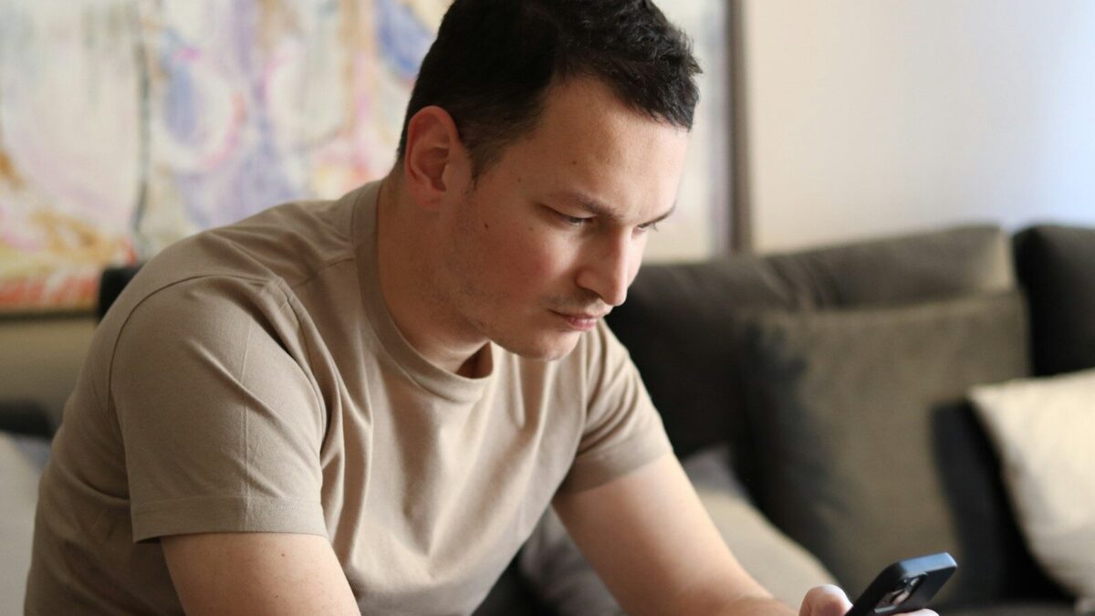 a man sitting on a couch looking at his cell phone
