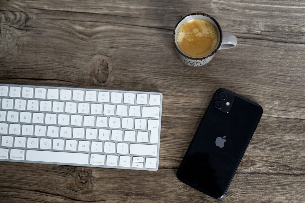 a cup of coffee next to a keyboard and a phone