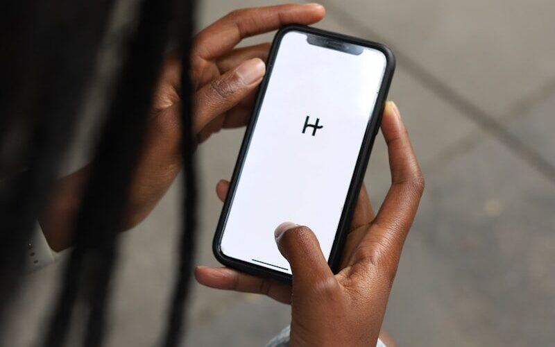 a woman holding a cell phone with a h on the screen