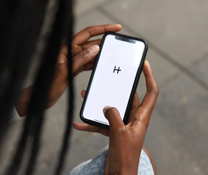 a woman holding a cell phone with a h on the screen