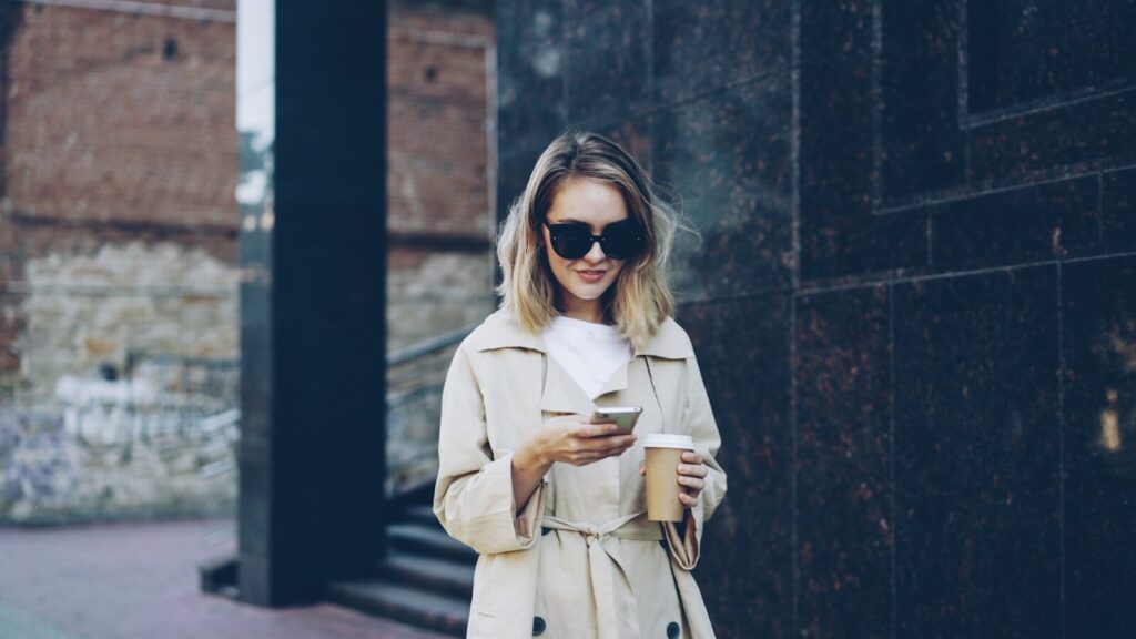 Woman with coffee and phone on city street