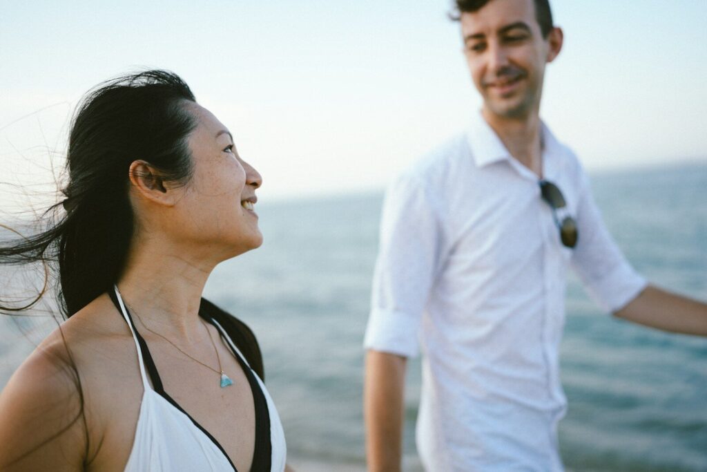 Couple smiling at each other by the ocean