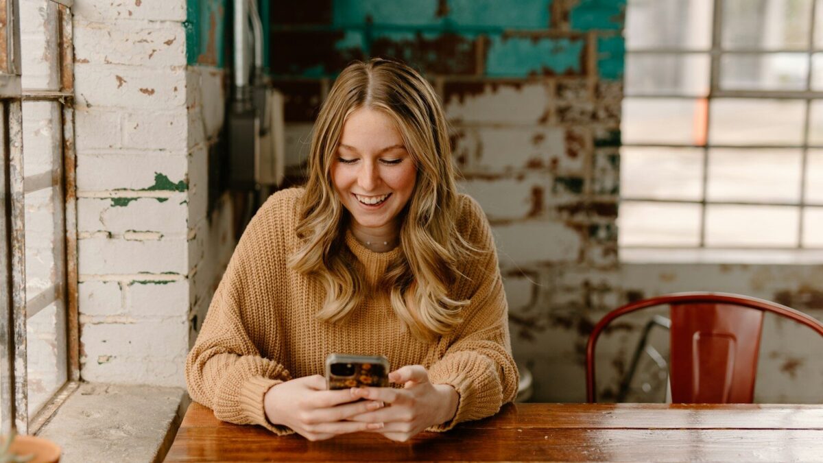 a woman sitting at a table looking at her cell phone