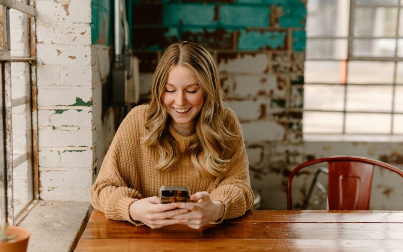 a woman sitting at a table looking at her cell phone