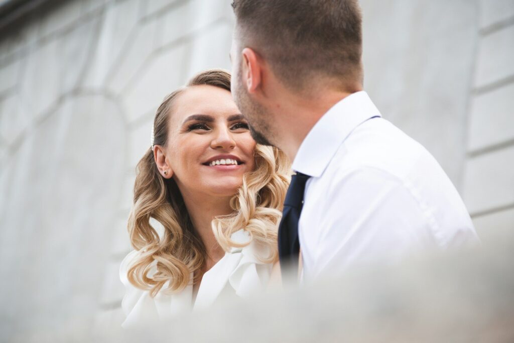 Bride and groom smiling at each other outdoors