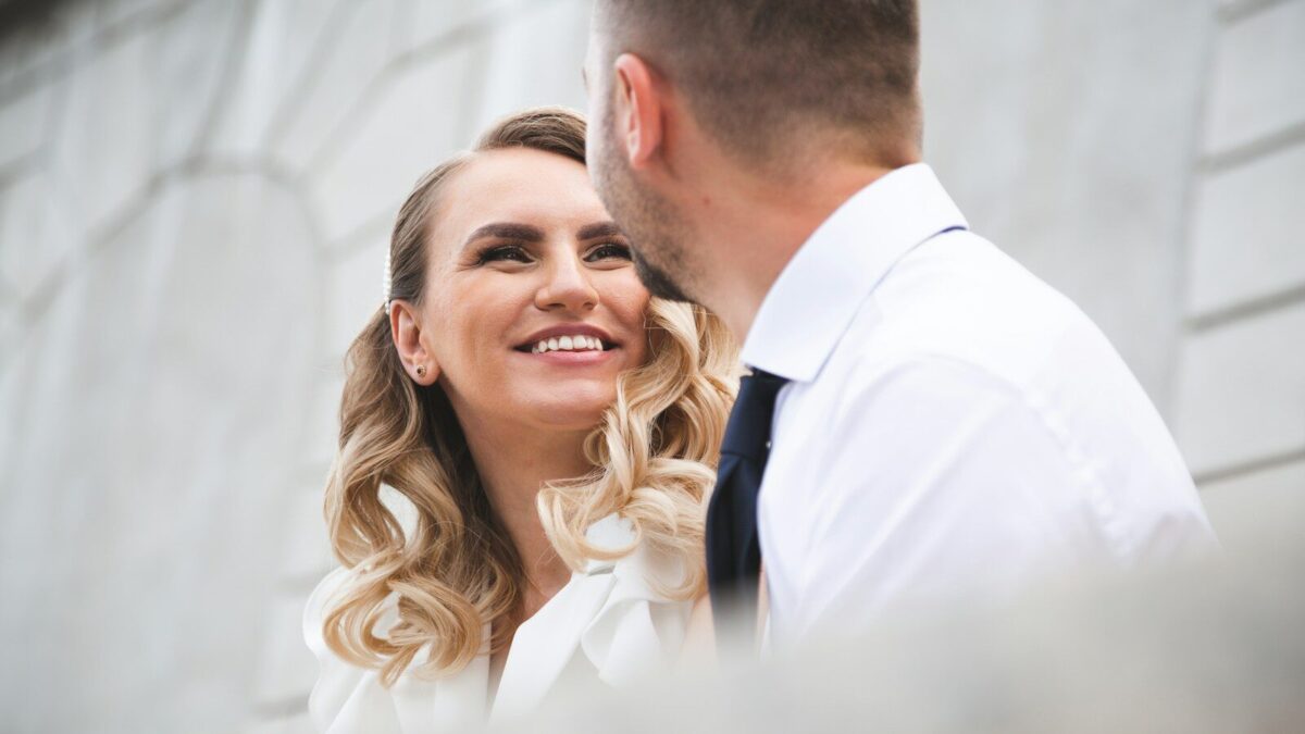 Bride and groom smiling at each other outdoors