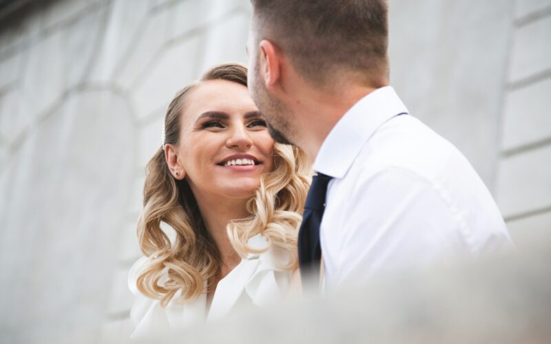 Bride and groom smiling at each other outdoors