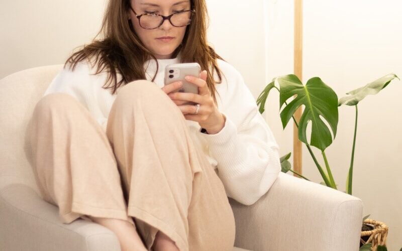 a woman sitting in a chair holding a cell phone