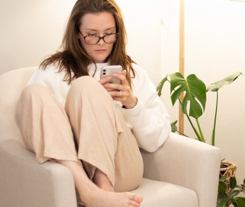 a woman sitting in a chair holding a cell phone