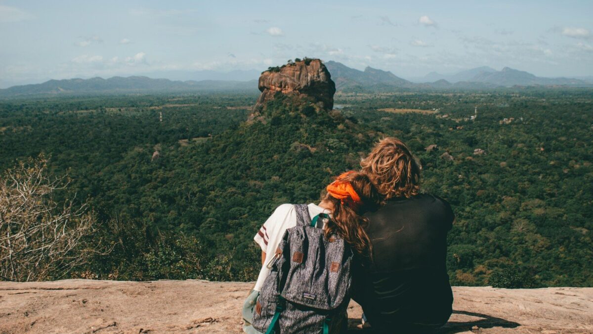 man and woman sitting beside cliff