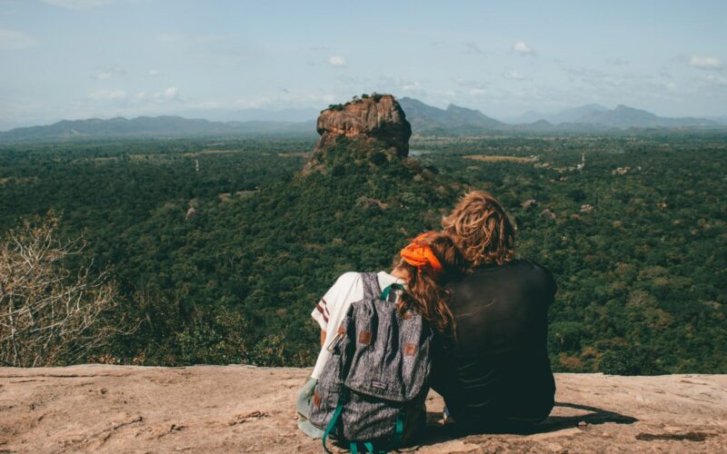 man and woman sitting beside cliff