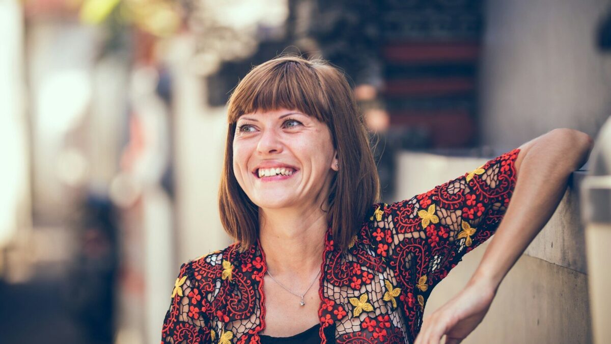 woman in floral-themed cardigan leaning on fence in bokeh photography
