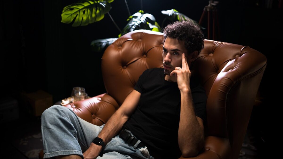 a man sitting in a brown chair talking on a cell phone