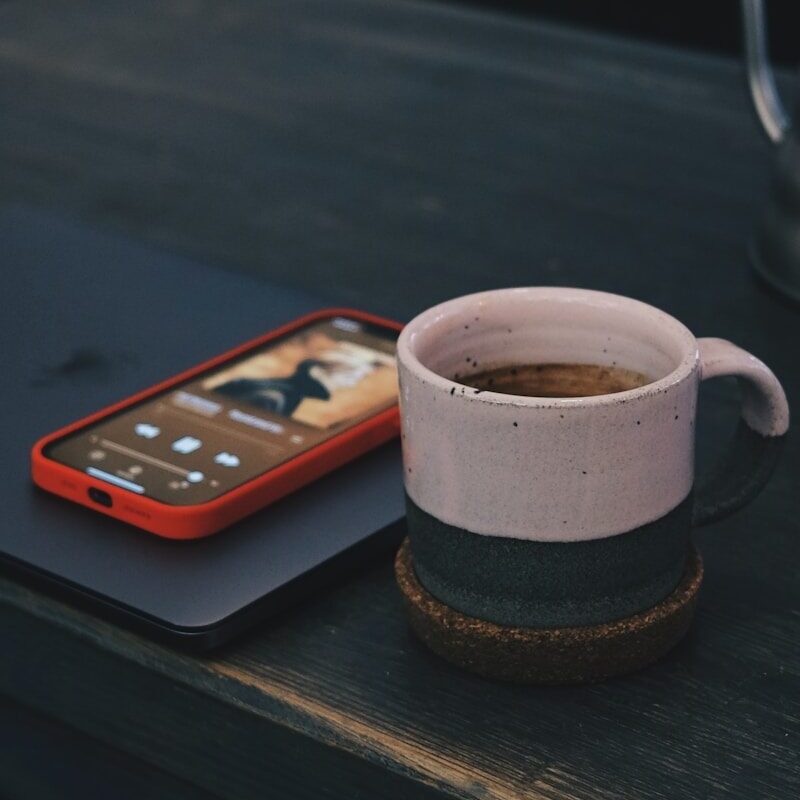 white and black ceramic mug on black wooden table