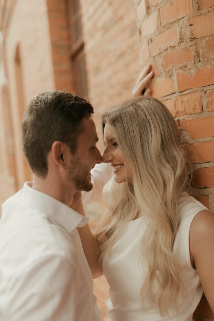 Couple smiling at each other by brick wall