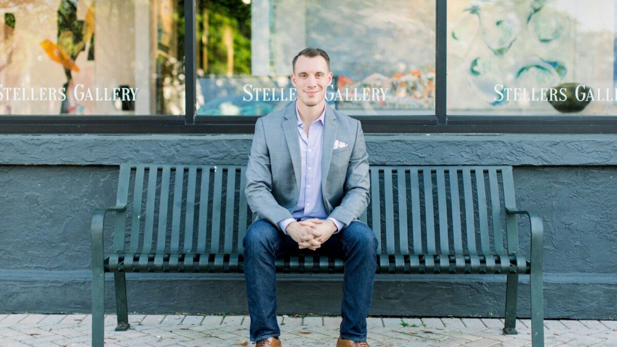 man in gray suit jacket sitting on black bench