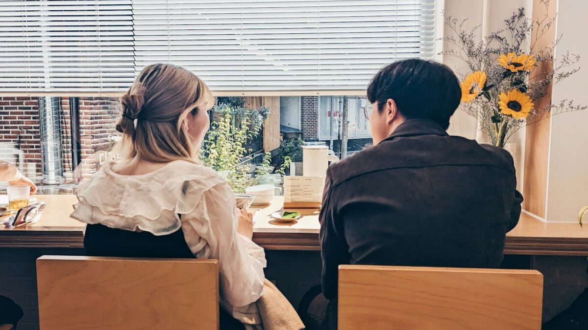 a man and a woman sitting at a table in front of a window