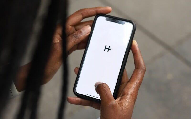 a woman holding a cell phone with a h on the screen