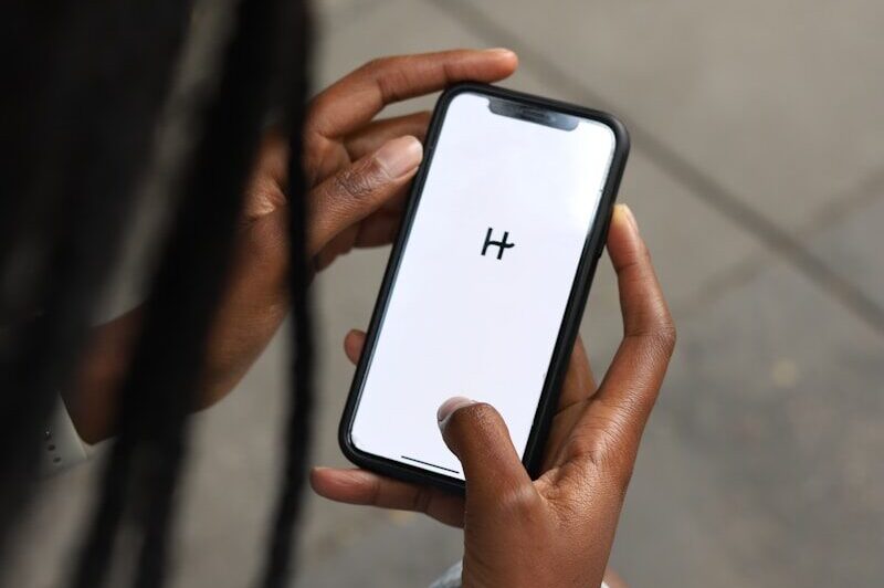a woman holding a cell phone with a h on the screen